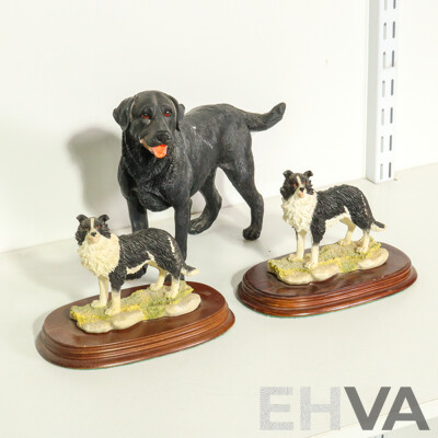 Three Resin Dog Figurines: Border Collies on Wooden Bases and a Labrador